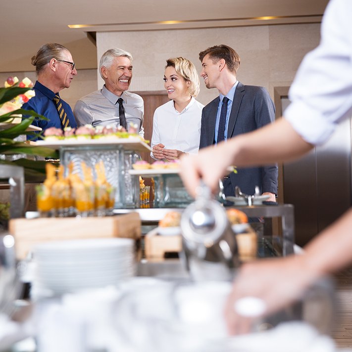 vier-laecheln-geschaeftsleute-am-buffet-table.jpg